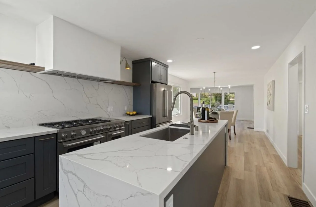 Remodeled kitchen with white cabinetry and a marble island